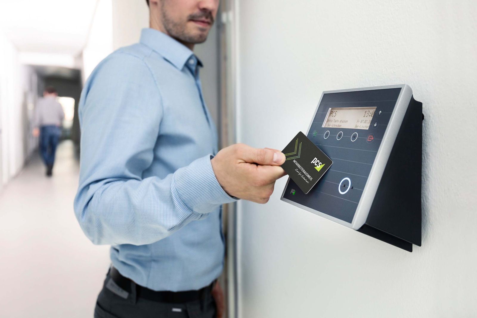 Wall-mounted card access reader with display and function buttons being tapped with a card